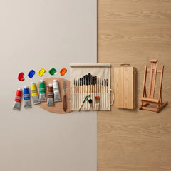 A wall-mounted wooden art kit display on a split beige and wood panel background, showing paint tubes, a paint brush roll, a wooden palette, a small wooden easel, and a wooden storage cabinet.