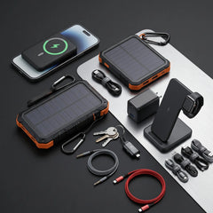 A rugged solar power bank set displayed on a dark surface, including two solar chargers with orange trim, a smartphone showing wireless charging, a wall charger, a black stand, cables, carabiners, and keys.