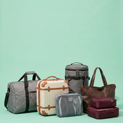 A collection of travel luggage and bags arranged on a solid mint green background, including a gray duffel bag, a cream suitcase with brown trim, a gray mesh pouch, a dark gray backpack, a brown tote bag, and two burgundy carry-on cases.