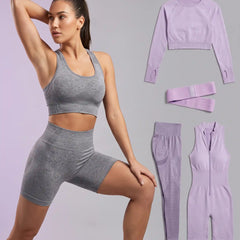 A woman models a gray ribbed sports bra and matching high-waisted biker shorts, with additional matching workout pieces in light purple displayed on the right against a pale lavender background.